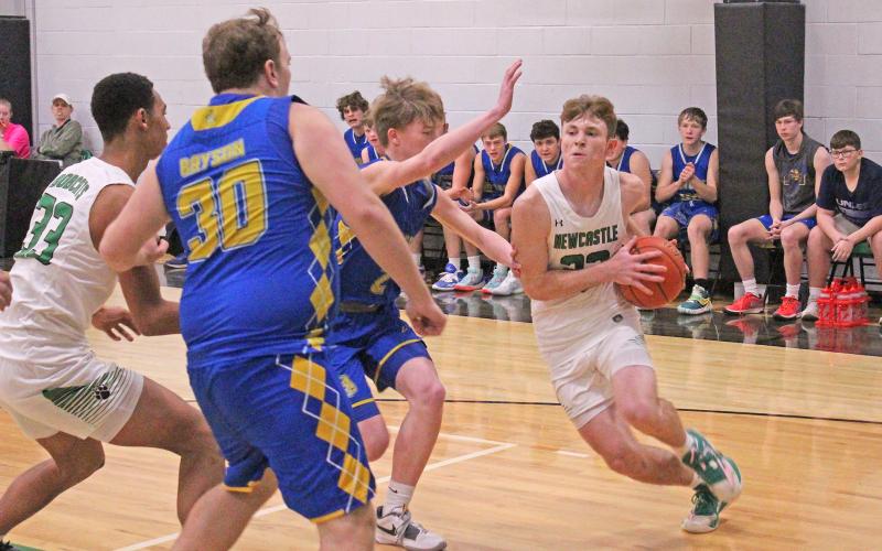 (TC GORDON | THE GRAHAM LEADER) Newcastle senior Isaac King (22) drives the baseline while two Bryson defenders try to get in his way. The Bobcats defeated the Cowboys 43-26 last Friday, Feb. 9 and clinched their spot in the playoffs.