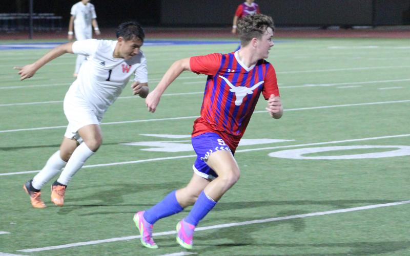 (TC GORDON | THE GRAHAM LEADER) Graham’s Easton Hedge (99) moves the ball up the field while a defender chases him during one of the team’s district games earlier this season. The Steers took a loss to Hirschi 2-0 this past Monday, Feb. 12.