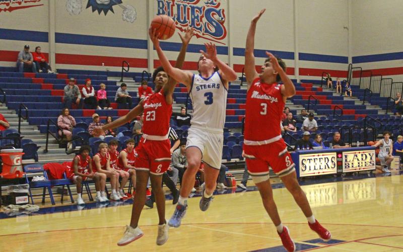 (TC GORDON | THE GRAHAM LEADER) Graham’s Tyson Weaver attempts a driving layup while two Sweetwater defenders try to block it during the teams’ game Saturday, Nov. 18. The Steers held on for a close 69-66 win over the Mustangs.