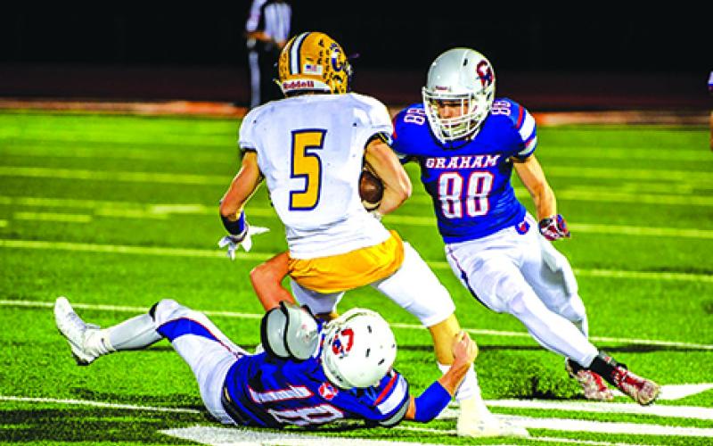 Graham’s Cy Holt (18) holds on to Godley running back Jeremy Carter as teammate Kalon Walker (88) prepares to run in for a tackle during the Steers bi-district playoff game last week from Porcupine Stadium in Springtown. Leader photo by David Flynn