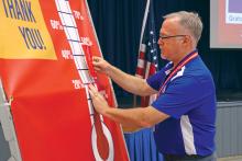 (THOMAS WALLNER | THE GRAHAM LEADER) Graham High School Principal Joe Gordy places a portion of the thermometer which shows how far the Graham Area United Way is to its $100,000 goal.