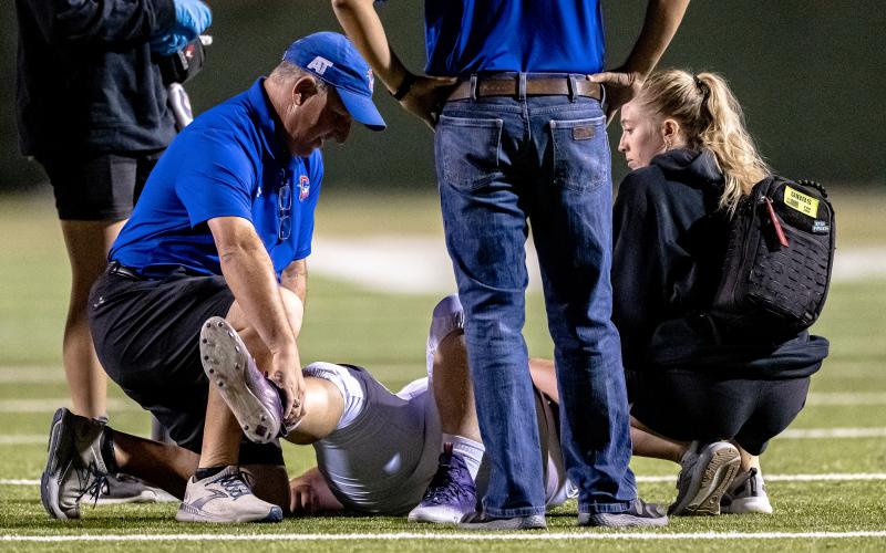 (DAVID FLYNN | CONTRIBUTED PHOTO) Graham athletic trainer in Mike Carroll helps to treat Steers player on the field during a game against the Wichita Falls Coyotes in September 2022.