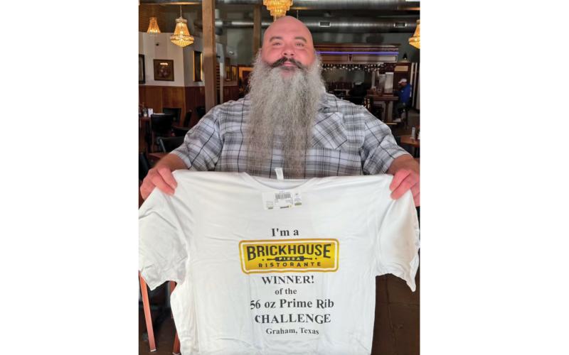 (BRICKHOUSE PIZZA & TAPROOM | CONTRIBUTED PHOTO) Andrew Clinton holds up a T-shirt he won for completing the Brickhouse Pizza & Taproom 56-ounce Prime Rib Challenge. The challenge was a way for him to jumpstart his weight loss goals. 