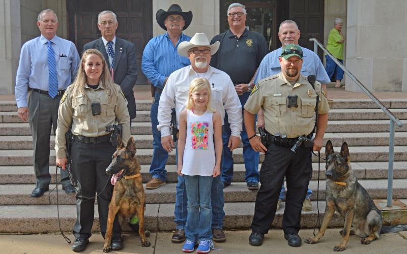 (ARCHIVE PHOTO | THE GRAHAM LEADER) K-9 Handlers Devin Wright and Samantha Muncy pose in March 2018 with their K-9 partners, Rocky and Sam, along with members of the Young County Commissioners Court, Sheriff Travis Babcock and Haven Snow, who raised money to help fund the purchase of Rocky.
