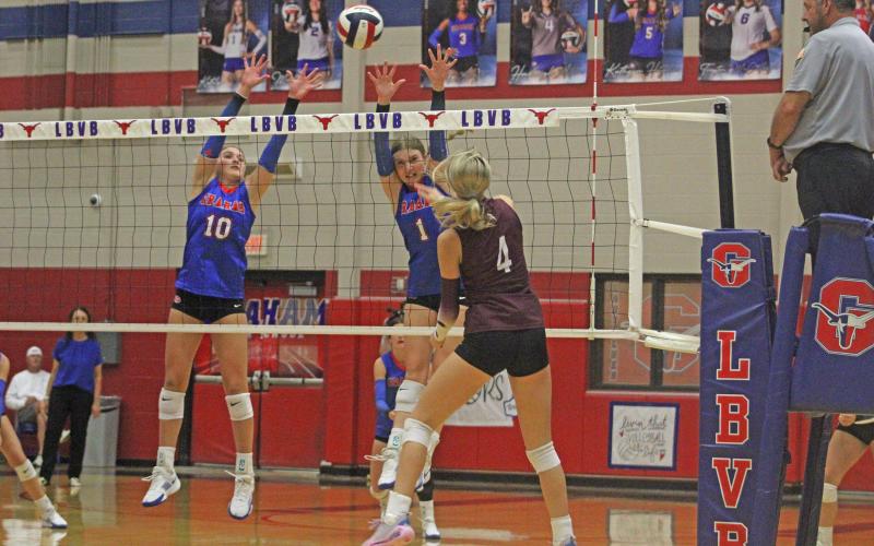 (ALEX HAVARDANKSY | THE GRAHAM LEADER) Emily Hughes, 10, and Katy McGehee, 1, team up for a block attempt in one of their matches. The Lady Blues lost to the Honeybees in four sets Tuesday, Sept. 30.