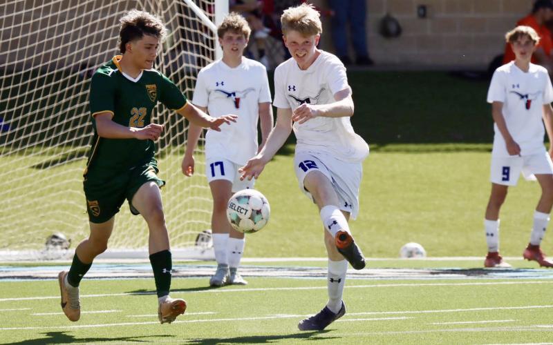(KYLIE BAILEY | THE GRAHAM LEADER) Steer Jacob Collins (12) kicks the ball away during the bi-district matchup with Cooper Wilde (17) watching from behind. The Steers fell 3-0 in the game Friday, March 20 in Canyon.