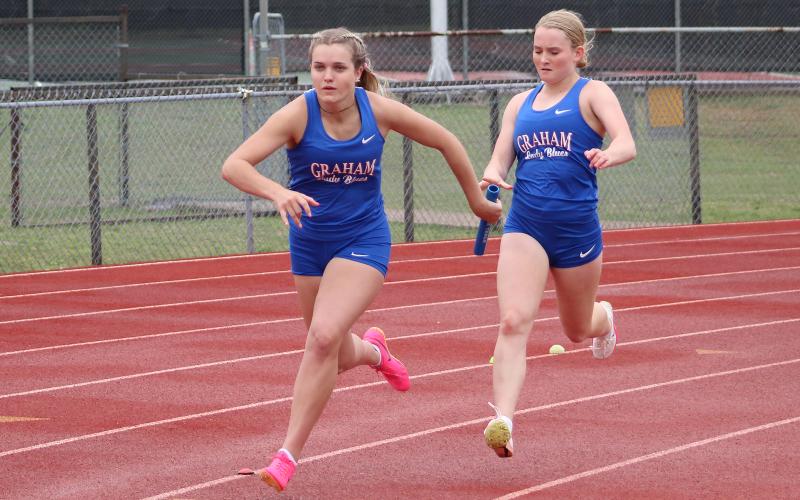 (TC GORDON | THE GRAHAM LEADER) Graham’s Olivia Pettus (right) passes off the baton to Kaden Atwood (left) during the varsity girls 4x100 relay at a meet Thursday, March 7 in Comanche.