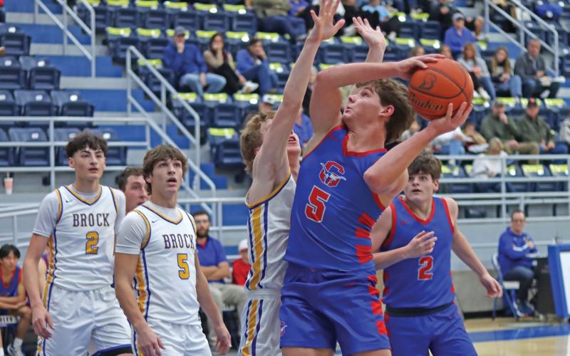 (THOMAS WALLNER | THE GRAHAM LEADER) Cooper Corley jumps over Brock defenders to attempt to lessen the scoring gap brought by Brock during their matchup Saturday, Jan. 11. The Steers fell 89-28 in their district opener.