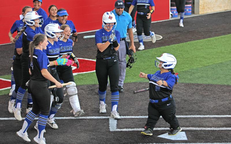 (ALEX HAVARDANSKY | THE GRAHAM LEADER) Katie Parker reaches home plate and is swarmed by her Lady Blues teammates during a special tribute to Parker in the team’s matchup Tuesday, April 15. Parker was given honorary recognition from the team for their senior night.