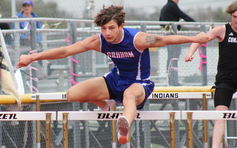 (TC GORDON | THE GRAHAM LEADER) Graham’s Zathin Reyes leaps over a hurdle during one of the two hurdle events the senior competed in at a meet Thursday, March 7 in Comanche.