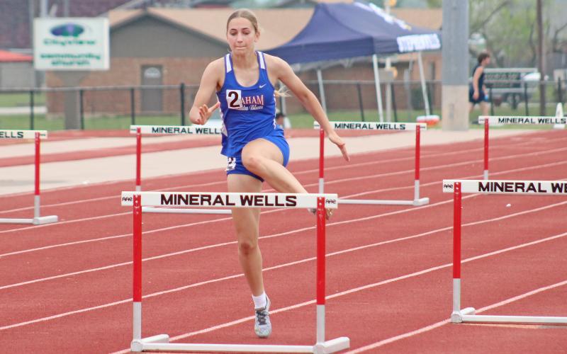 (TC GORDON | THE GRAHAM LEADER) Ava Street of the Lady Blues begins her jump over a hurdle during the 300-meter Hurdles event at the district track meet in Mineral Wells this past Monday, April 1.