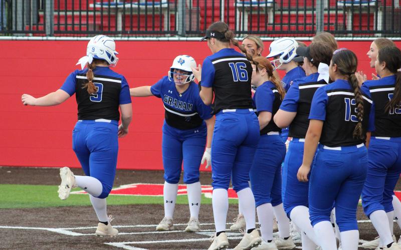 (TC GORDON | THE GRAHAM LEADER) Graham third baseman Emily Lawson (9) is welcomed to the plate by her teammates after she hit a huge home run during the team’s game Tuesday, April 16. The Lady Blues defeated Glen Rose 5-3 on Senior Night.