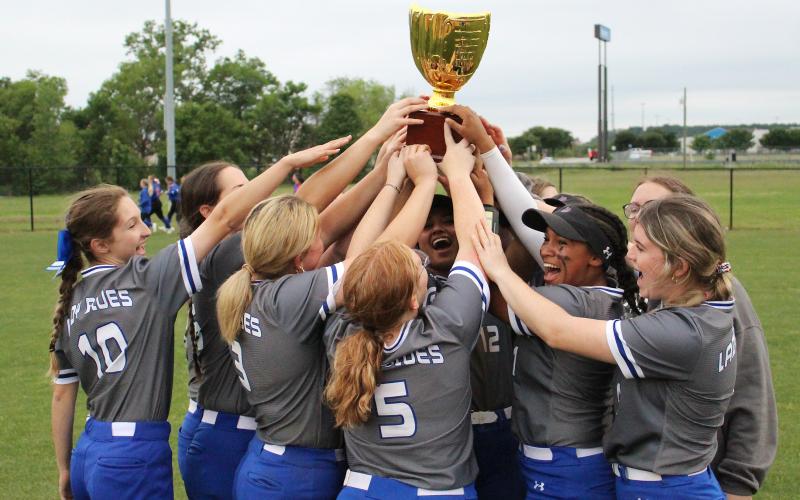 (TC GORDON | THE GRAHAM LEADER) The Lady Blues hoist the district championship trophy in the air after defeating Mineral Wells 13-7 to win first place in the district standings. The team finished with a 6-2 district record to earn the title.