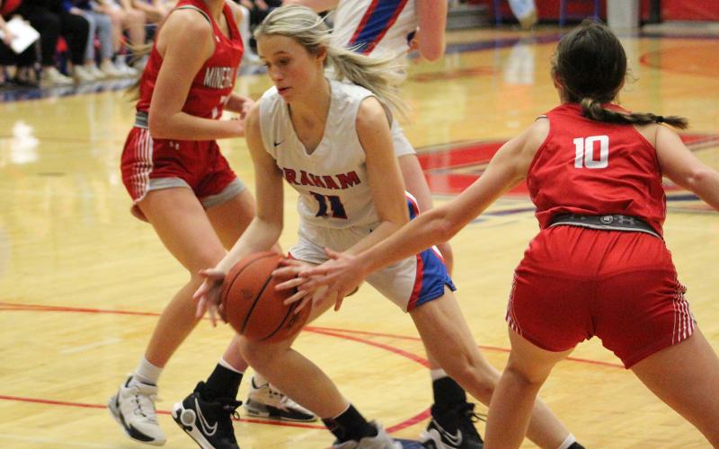 (TC GORDON | THE GRAHAM LEADER) Lady Blues senior Maddie Franklin (11) dribbles through two Mineral Wells defenders Friday, Jan. 19 during Graham’s Senior Night. The Lady Blues came up short and took the loss 22-19.
