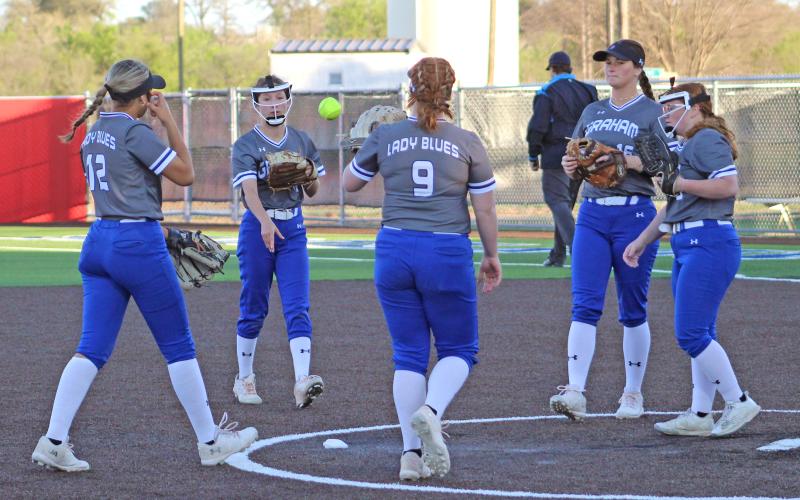 (TC GORDON | THE GRAHAM LEADER) The Lady Blues’ infield meets at the pitcher’s circle after Reese Calhoun (far right) struck out a Brownwood hitter during Graham’s 12-0 win over the Lady Lions this past Monday, March 25.