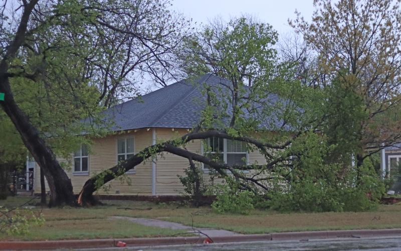 (THOMAS WALLNER | THE GRAHAM LEADER) A home at the corner of East Street and Second Street with a tree split down the middle. Trees and tree limbs are scattered throughout the city of Graham due to earl-morning storms.