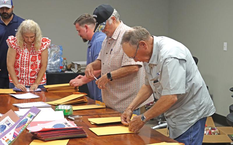 (THOMAS WALLNER | THE GRAHAM LEADER) Volunteers and American Legion Post 34 members seal packages containing letters and pictures to be included with care packages for U.S. Marines across the globe.