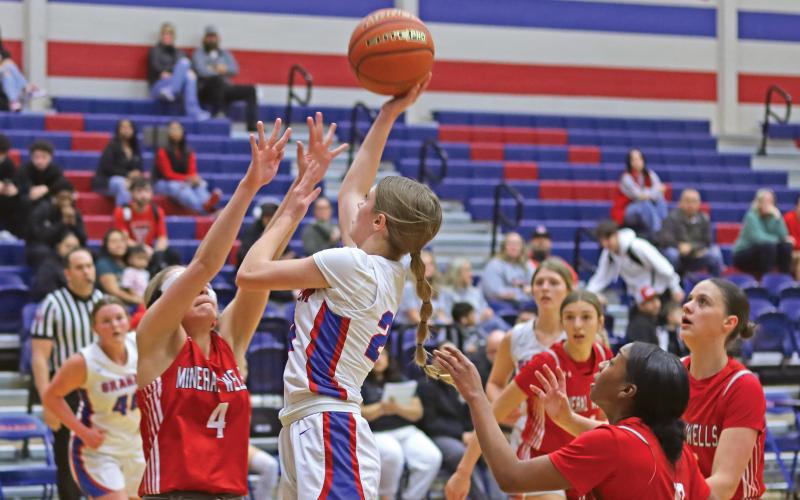 (THOMAS WALLNER | THE GRAHAM LEADER) Katy McGeehee of the Lady Blues jumps over Mineral Wells defenders as she attempts a shot Friday, Jan. 17. The Graham team picked up its first district win during the midpoint of their schedule.