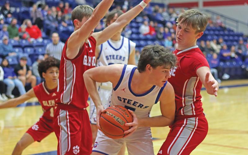 (THOMAS WALLNER | THE GRAHAM LEADER) Cooper Corley looks around a Glen Rose defender as he looks to pass and make a play Tuesday, Jan. 21. Despite and early lead and a continued effort, the Steers fell to the Tigers.