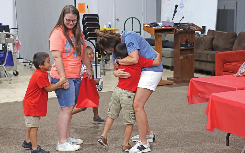 (ARCHIVE PHOTO | THE GRAHAM LEADER) Children hug a volunteer at the Graham Up Graham event held at Eastside Church of Christ in 2024. The back-to-school giveaway event will happen this year at 6 p.m. Sunday, Aug. 3.