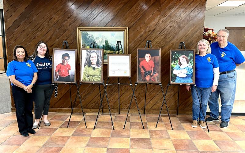 (ISABEL SMITH | CONTRIBUTED PHOTO) Members of the Young County Child Welfare Board and Heart Gallery of Northwest Texas stand Wednesday, Oct. 29 next to a Heart Gallery at Interbank. Galleries are also located at the Young County Courthouse and Ciera Bank.