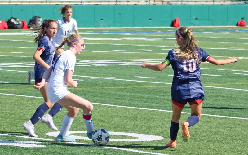 (ALEX HAVARDANSKY | THE GRAHAM LEADER) Macee Wilde maneuvers the ball past two Lady Patriots defenders to move the ball to their side of the field and attack their net late in the first half of their matchup Tuesday, March 25. Despite multiple scoring opportunities, the Lady Blues were held to zero points.