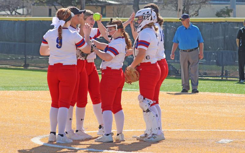 (MIKE WILLIAMS | CONTRIBUTED PHOTO) The Lady Blues’ infield gathers in the pitching circle to high-five and pump each other up before another inning during one of the team’s games in the Abilene tournament over the past weekend.