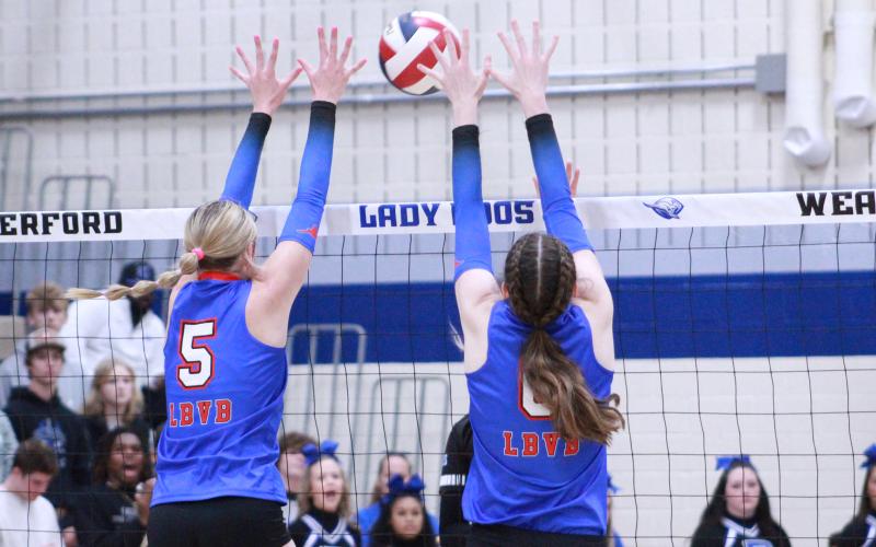 (TC GORDON | THE GRAHAM LEADER) Juniors Braylee Mayes (5) and Emilee Gordy (6) leap into the air together to try to block one of Decatur’s hits. The Lady Blues lost to the Lady Eagles in three sets in the area round playoff game.