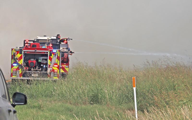 (THOMAS WALLNER | THE GRAHAM LEADER) Young County volunteer fire departments spray water at a fire Sunday, Sept. 21 near FM 209 to stop the spread of the fire over the road. Many local firefighters worked throughout the day to help contain the fire.