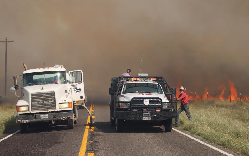 (THOMAS WALLNER | THE GRAHAM LEADER) A Young County Precinct 4 water truck and an Eliasville VFD truck spring into action following a grassfire on FM 209 jumping the road Sunday, Sept. 21. 