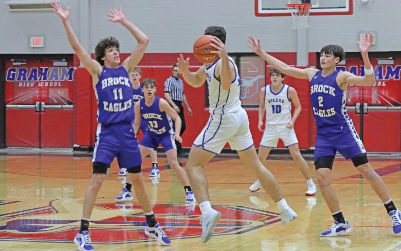 (LIAM BAILEY | THE GRAHAM LEADER) Ty Thompson jumps to throw the ball to an open teammate while Brock defenders jump to stop him Tuesday, Jan. 28. Thompson was the top scorer for the Steers during the game. 
