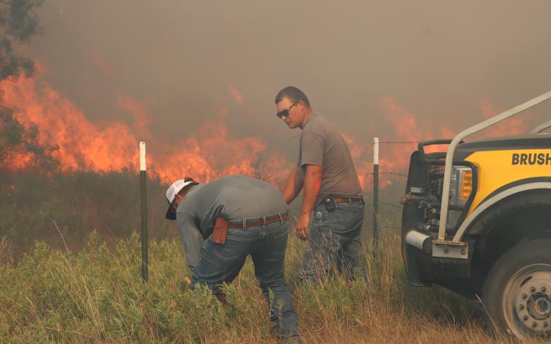(THOMAS WALLNER | THE GRAHAM LEADER) State and local fire units cut a fence Sunday, Sept. 21 to allow firefighters to move into an area where a grassfire had jumped FM 209. Local and state fire units quickly worked to stop the spread of the fire after it jumped the road.