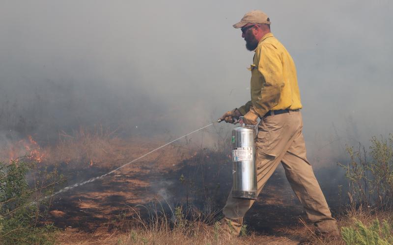(THOMAS WALLNER | THE GRAHAM LEADER) Texas Division of Emergency Management Young County Liaison Jarod Cook jumps out of his vehicle to stop a small fire. Cook, along with many other local and state firefighters, worked to contain the fire Sunday, Sept. 21.