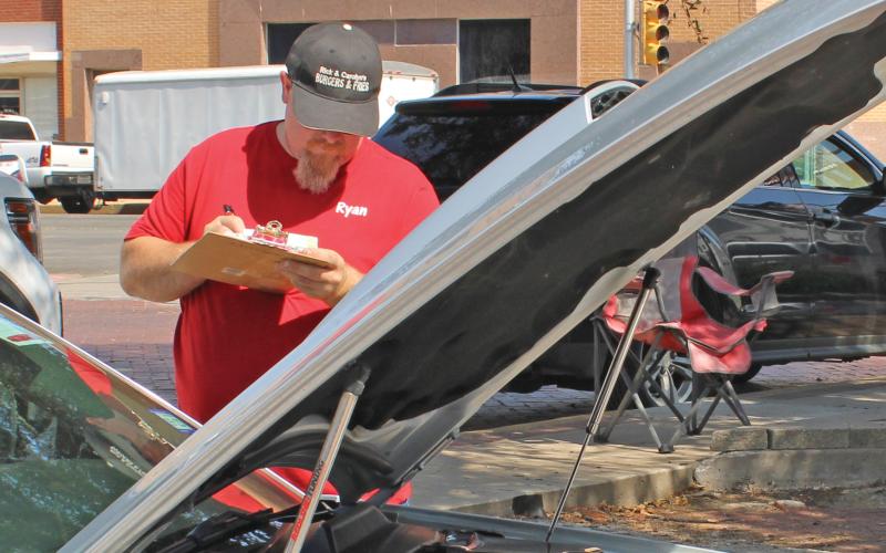 (ARCHIVE PHOTO | THE GRAHAM LEADER) A judge in the 12th annual Cars and Stars car show writes down on a scorecard. The event this year will return downtown Saturday, Oct. 12, with registration opening at 8 a.m.
