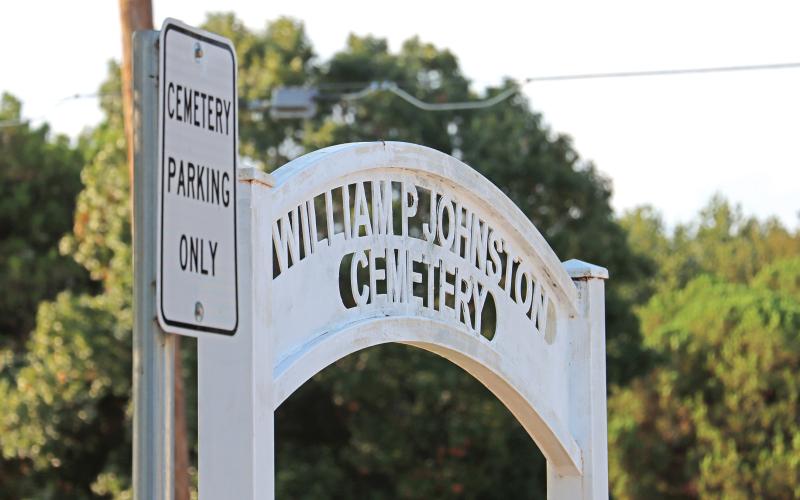 (THOMAS WALLNER | THE GRAHAM LEADER) The entranceway to the Oak Grove Colored - William P. Johnston Cemetery along with a sign showing parking at the cemetery. A ground penetrating radar survey found 14 possible unmarked graves in the city of Graham-owned cemetery parking area.