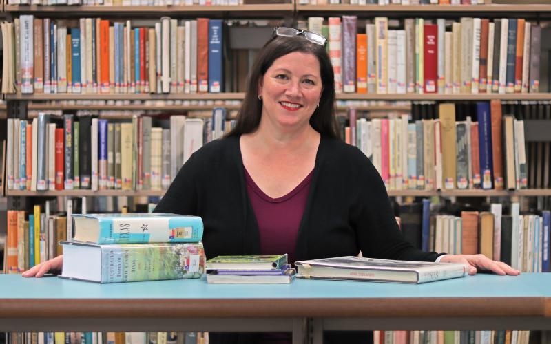 (THOMAS WALLNER | THE GRAHAM LEADER) New Library of Graham Director DeAnna Bullock poses with a selection of Texana books from the library. Bullock previously served as interim library director and was appointed to the position Thursday, Dec. 21 by the Graham City Council.