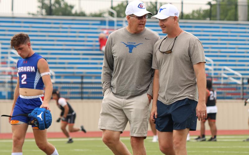 (KYLIE BAILEY | THE GRAHAM LEADER) Steers head coach Kenny Davidson (left) speaks with 7on7 coach Darby Brockway in May 2023 at Newton Field. Davidson will be retiring at the end of 2023-2024 school year.