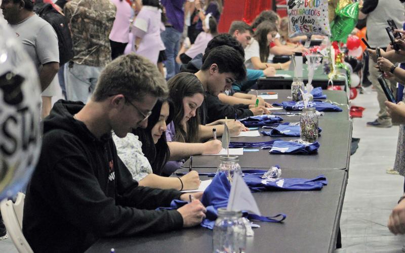 (ALEX HAVARDANSKY | THE GRAHAM LEADER) Students sign their offers to various schools at the Graham High School signing day ceremony Monday, May 12. 