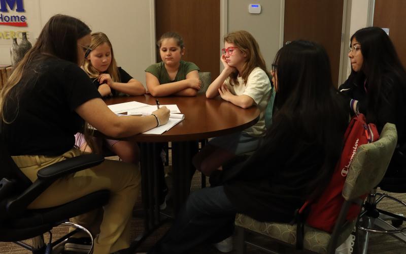 (THOMAS WALLNER | THE GRAHAM LEADER) Members of The 5 Reindeers group meet with Publisher Kylie Bailey of The Graham Leader to design their advertising for their hot chocolate business that will run in the newspaper. The students rotated through stations Wednesday, Oct. 22 to receive a loan and work on marketing their businesses.