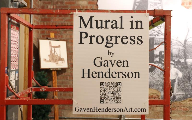 (THOMAS WALLNER | THE GRAHAM LEADER) A scissor lift inside the Young County Museum of History and Culture with a sign stating that local artist Gaven Henderson is working on a mural. Henderson is working on completing five murals for the museum, with the first almost completed.