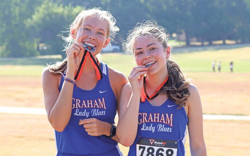 (ARCHIVE PHOTO | THE GRAHAM LEADER) Graham duo of Rebekah Gilbertson (left) and Sonya Clarke (right) bite their silver medals that they received for their second place finish Wednesday, Aug. 21 at the Nocona Relays. 