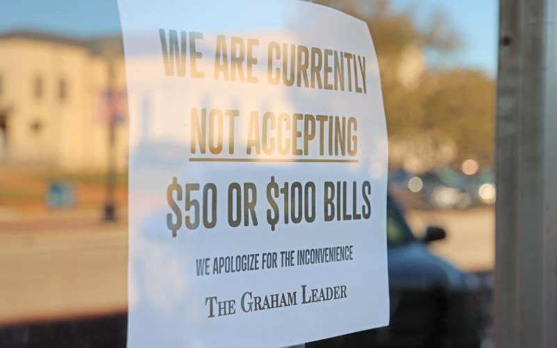 (THOMAS WALLNER | THE GRAHAM LEADER) A sign displayed on the front door of The Graham Leader office at 620 Oak St. in Graham stating the business is not accepting $50 or $100 bills. The sign was placed due to recent cases of counterfeit bills being used at downtown businesses.