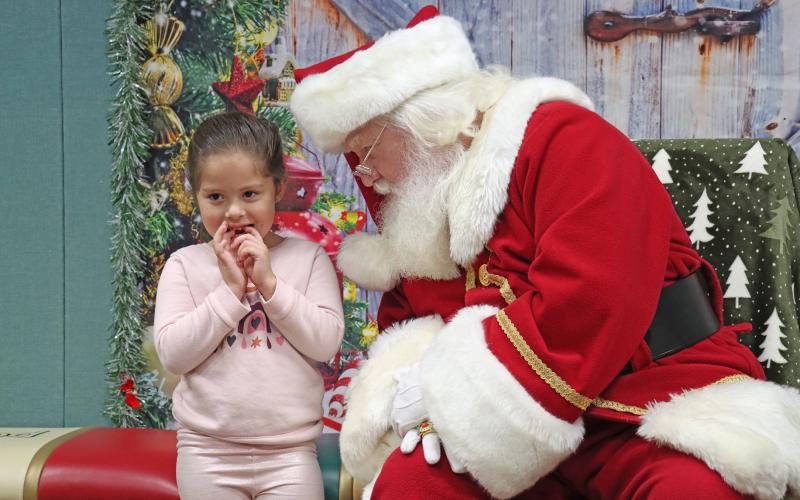 (THOMAS WALLNER | THE GRAHAM LEADER) Santa whispers to a visitor at the Santa at the Library event in December 2024. The event will return to the Library of Graham next week Saturday, Dec. 6.