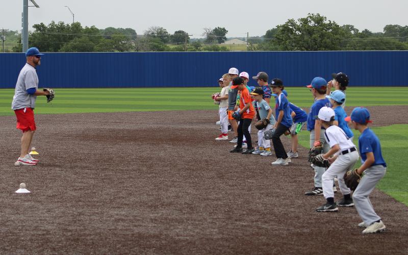 (ALEX HAVARDANSKY | THE GRAHAM LEADER) Allen McGee teaches campers fielding techniques at Steers baseball camp Tuesday, June 3. McGee serves as the Steers baseball head coach in Graham.