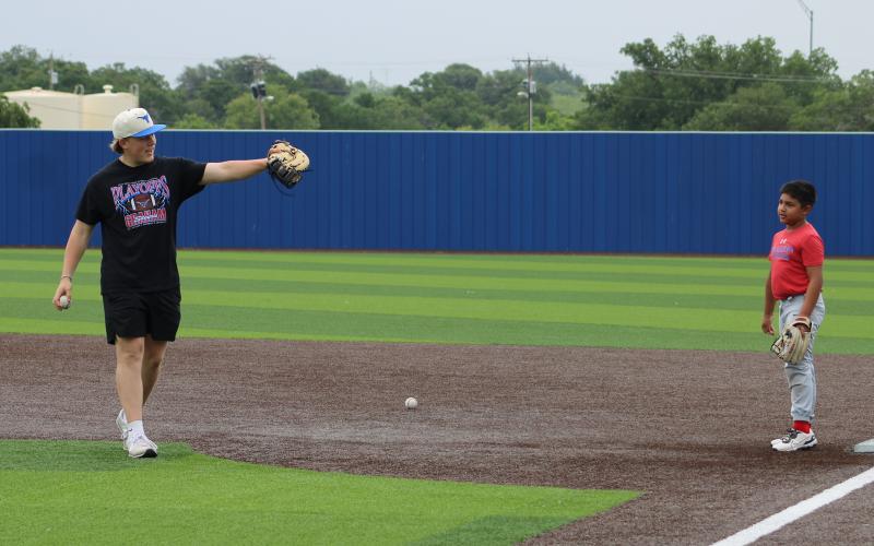 (ALEX HAVARDANSKY | THE GRAHAM LEADER) Recently graduated Steers first baseman Colter Johnson helps teach students how to pick ground balls at first base Tuesday, June 3. 
