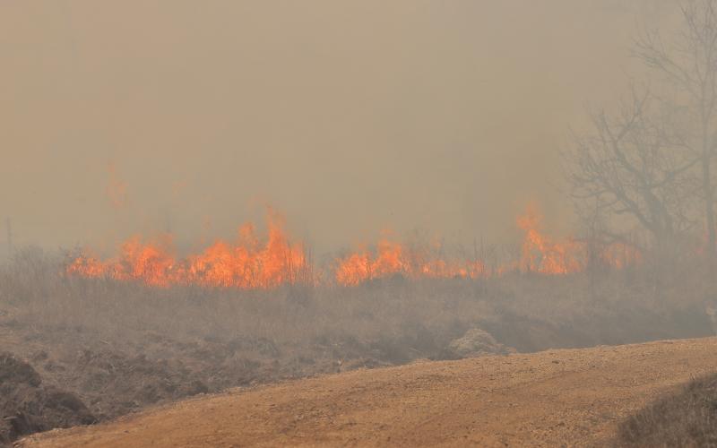 (THOMAS WALLNER | THE GRAHAM LEADER) Volunteer fire units fought a grass fire near the transmission lines Friday, March 14 off of Fish Creek Road. Dust and smoke filled the air as volunteers units fought gusts of wind. 