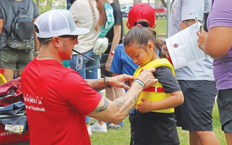 (ARCHIVE PHOTO | THE GRAHAM LEADER) Aaron Terasas fits a life jacket for a visitor at the 2024 Family Fun and Fishing event at Firemen’s Park in Graham. The event this year will be held at the same location Saturday, April 26.