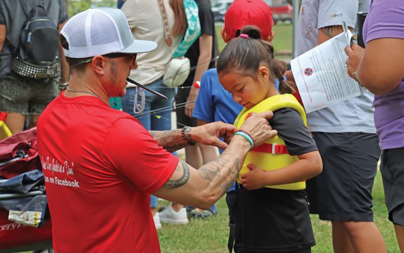 (ARCHIVE PHOTO | THE GRAHAM LEADER) Aaron Terasas fits a life jacket for a visitor of the 2024 Family Fun and Fishing event at Firemen’s Park. There will be a limited number of life jackets available at the event due to another life jacket giveaway event being held in the summer.
