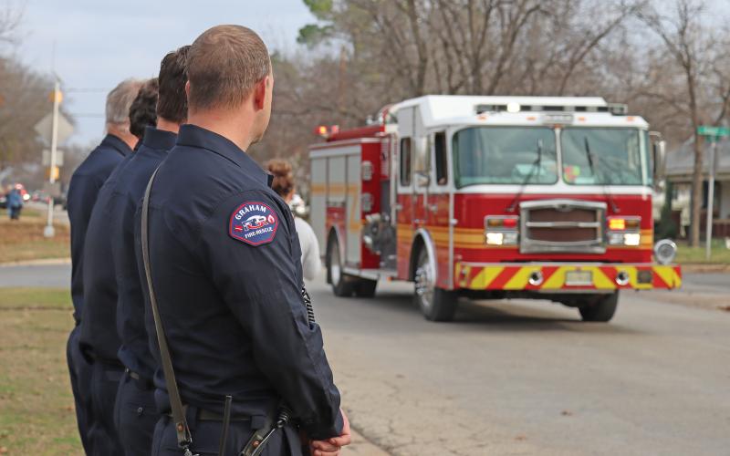 (THOMAS WALLNER | THE GRAHAM LEADER) Members of Graham Fire Rescue watch an escort for former fire chief Denny Covey who passed away Friday, Jan. 3. Members of the community lined the streets Sunday, Jan. 5 as first responders led Covey to Morrison Funeral Home.