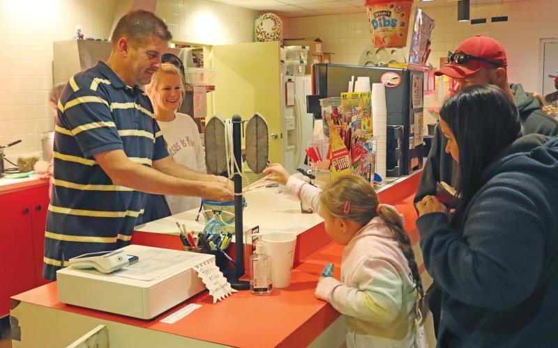 (THOMAS WALLNER | THE GRAHAM LEADER) Jett McFerrin (right) shows Mason McFerrin (middle) how to use the popcorn machine at the Graham Drive In theater concession stand with former owner Therrol DuBois overseeing Saturday, March 16.
